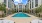 Luxurious apartment pool area surrounded by modern architecture and lush greenery, offering ample sun loungers and a serene atmosphere at Elina in Easton Park
