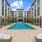 Luxurious apartment pool area surrounded by modern architecture and lush greenery, offering ample sun loungers and a serene atmosphere at Elina in Easton Park