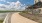 Scenic riverside walkway leading to a modern apartment building with covered seating, perfect for relaxed living in Austin